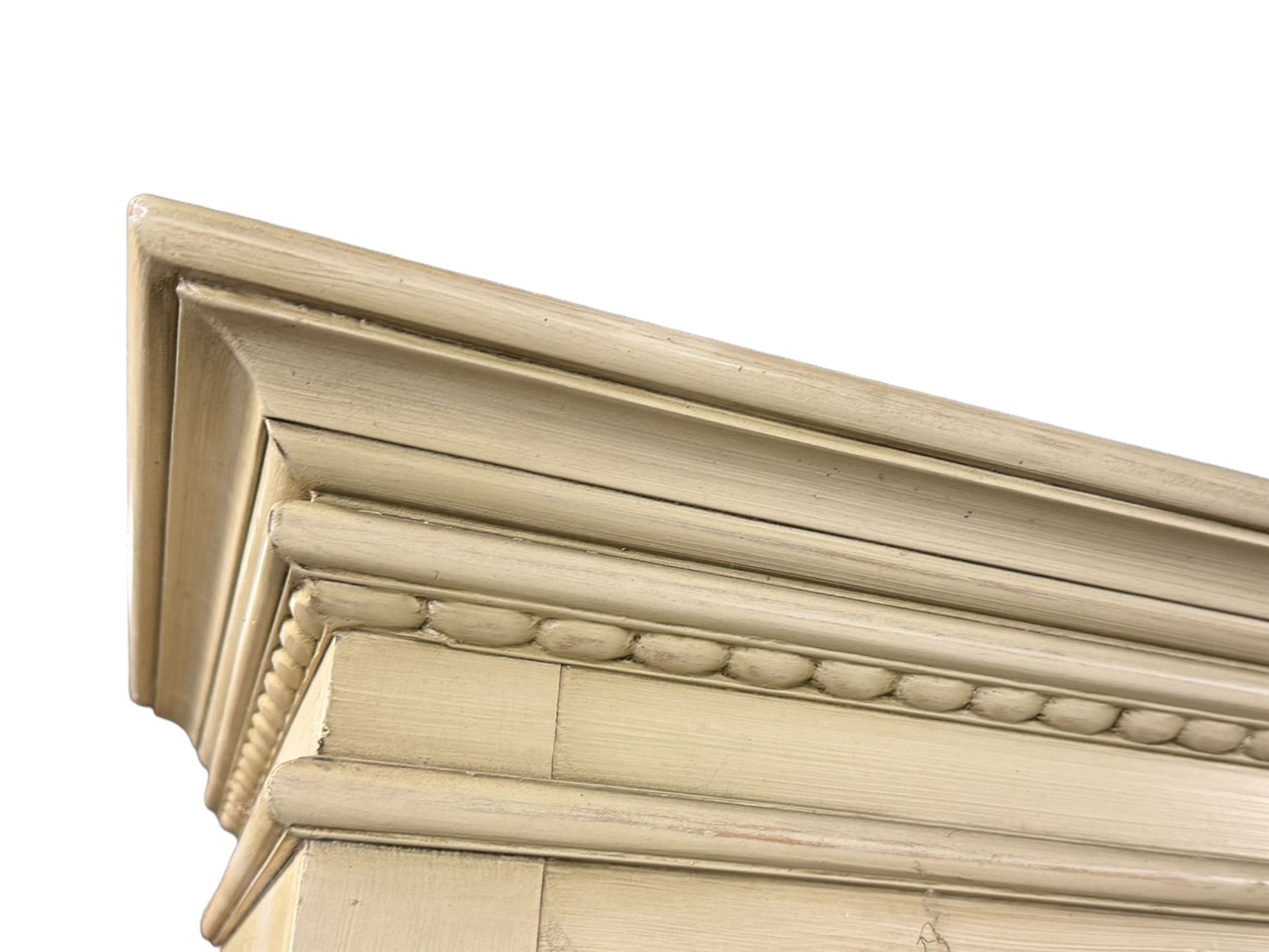 Provincial style cream painted bookcase, projecting cornice over dentil moulding, scalloped frieze above three open shelves, lower section fitted with two drawers, on bracket feet with apron