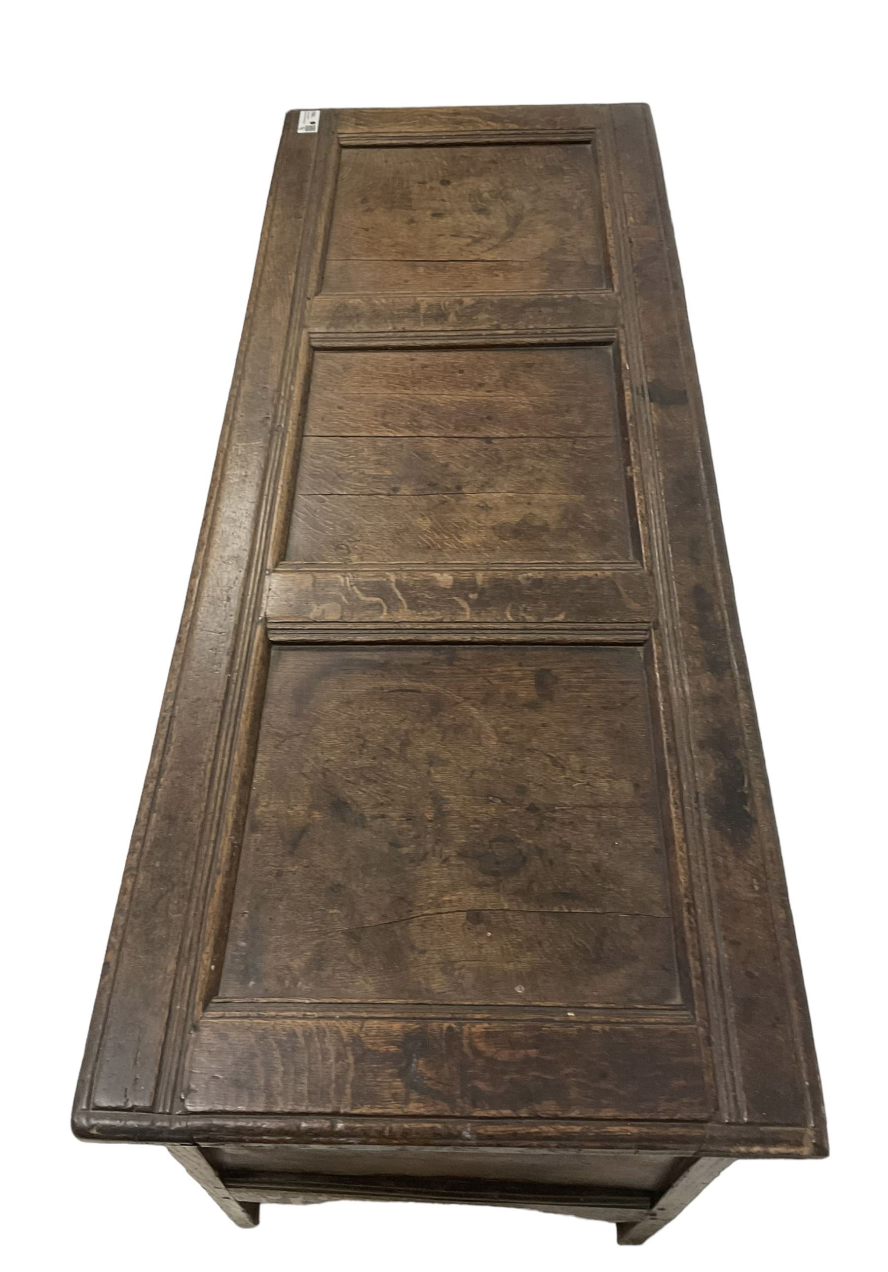 18th century oak coffer or chest, rectangular hinged panelled top with moulded frame enclosing candle box, the frieze carved with foliate S-scrolls over a quadruple panel front decorated with carved lozenges, on stile supports