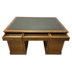 Late 19th century twin pedestal oak partner's desk, rectangular top with inset green leather writing surface, fitted with nine graduating drawers to each side, the rear drawers enclosed by panelled cupboards