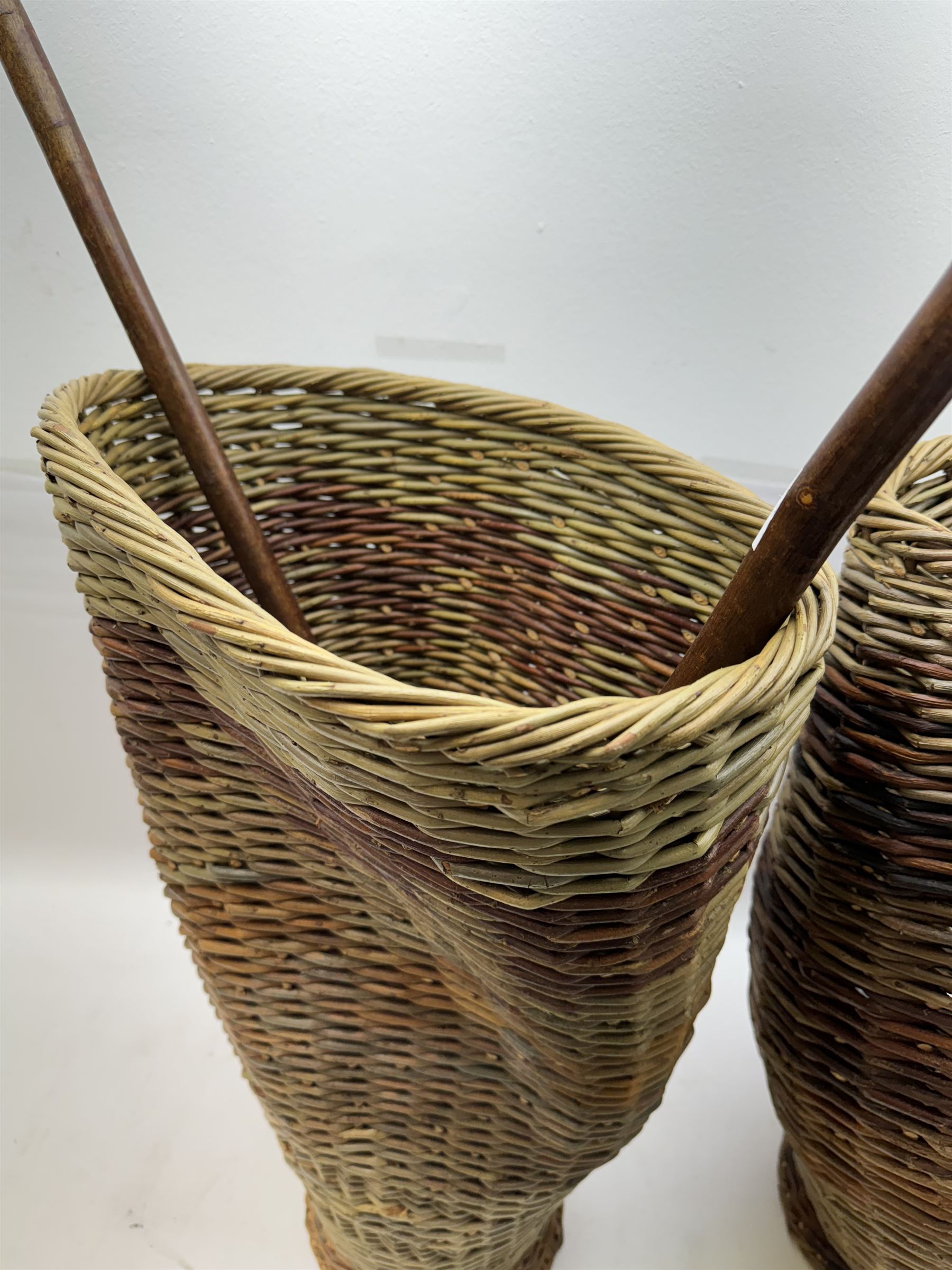 Two rattan baskets, of circular abstract form, together with two crook walking stick, basket H62cm 