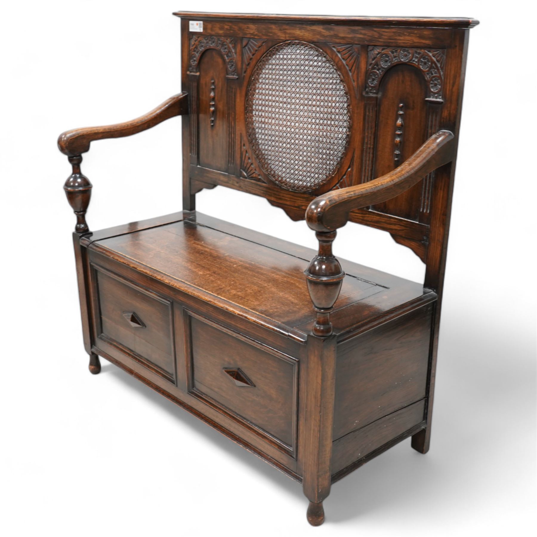 Early 20th century oak hall bench, circular caned back enclosed by panels decorated with flowerhead carved arcades, hinged box seat, panelled front 