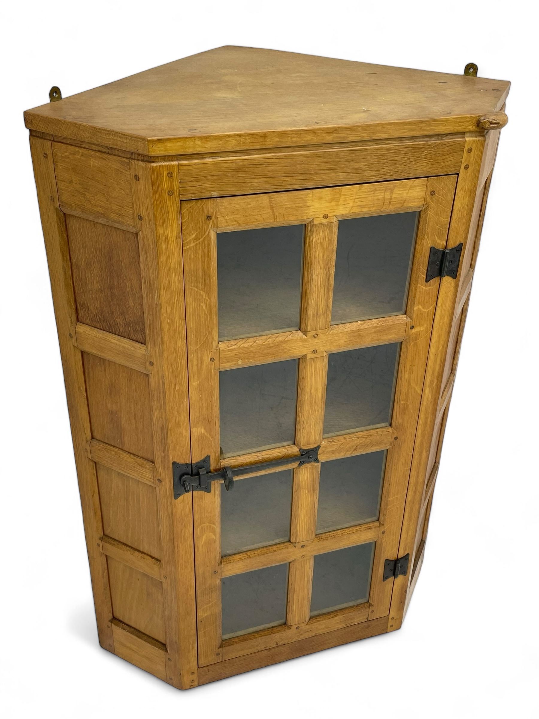 Rabbitman - oak corner cabinet, astragal glazed door enclosing three internal shelves, panelled upright corners, fitted with wrought metal hinges and latch, carved with rabbit signature, by Peter Heap, Wetwang 