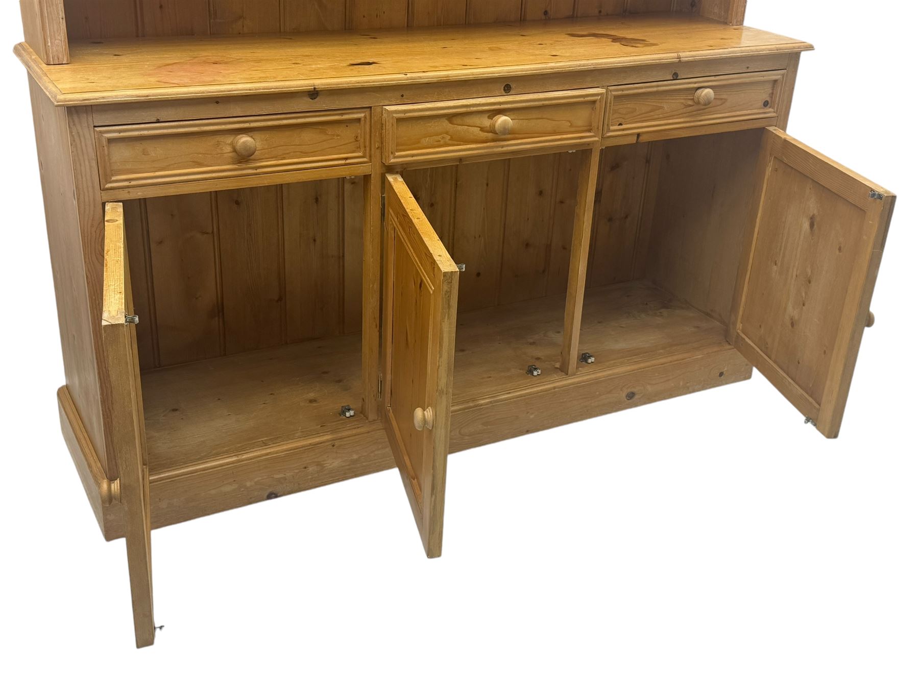 Traditional design waxed pine dresser, upper section with moulded cornice over scalloped frieze, fitted with two open shelves and four drawers, lower section with three drawers over three panelled cupboards, on plinth base