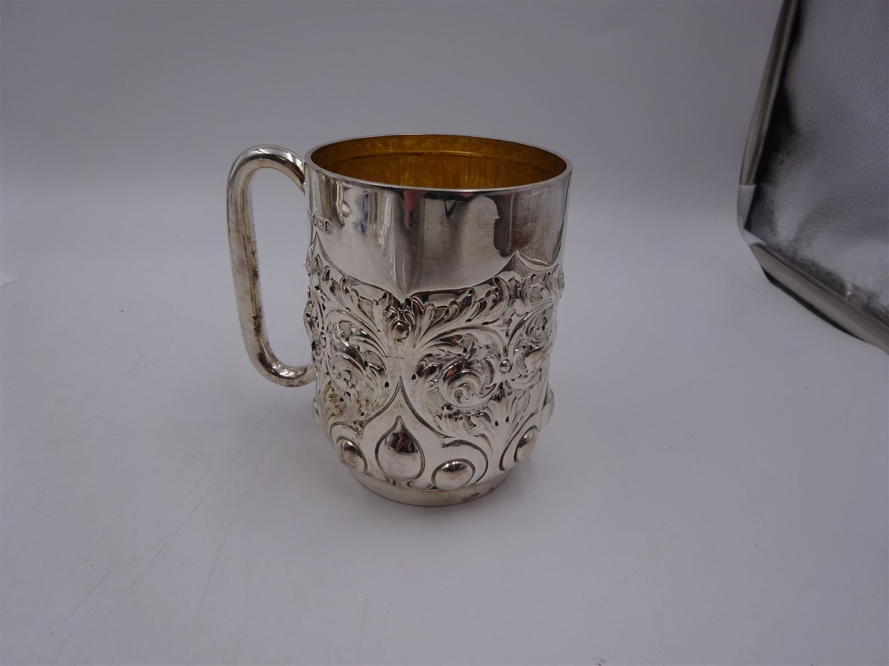 Late Victorian silver christening mug, with C handle and gilt interior, the body profusely embossed with floral and foliate decoration, hallmarked Atkin Brothers, Sheffield 1897, H10cm