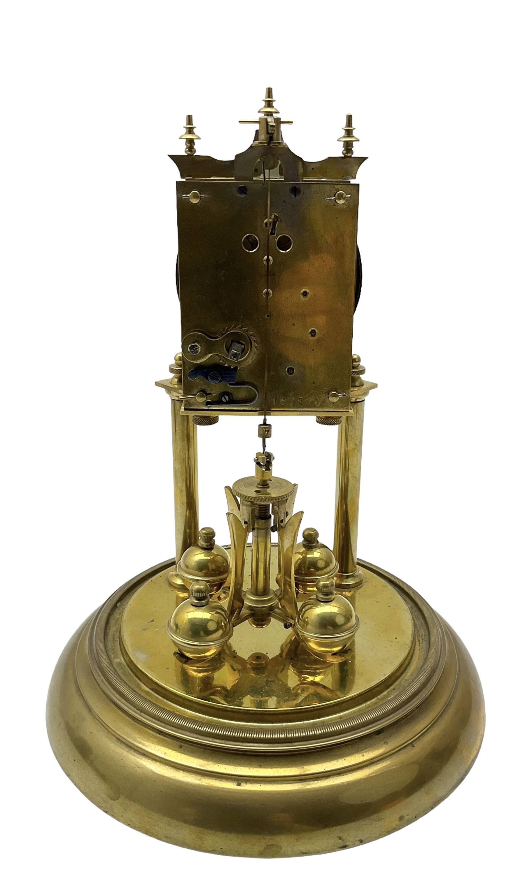 Continental- early-20th century torsion clock under a glass dome, movement raised on two pillars on a circular brass base, with an enamel dial, Roman numerals and spade hands, oscillating four ball circular pendulum. Torsion spring intact.