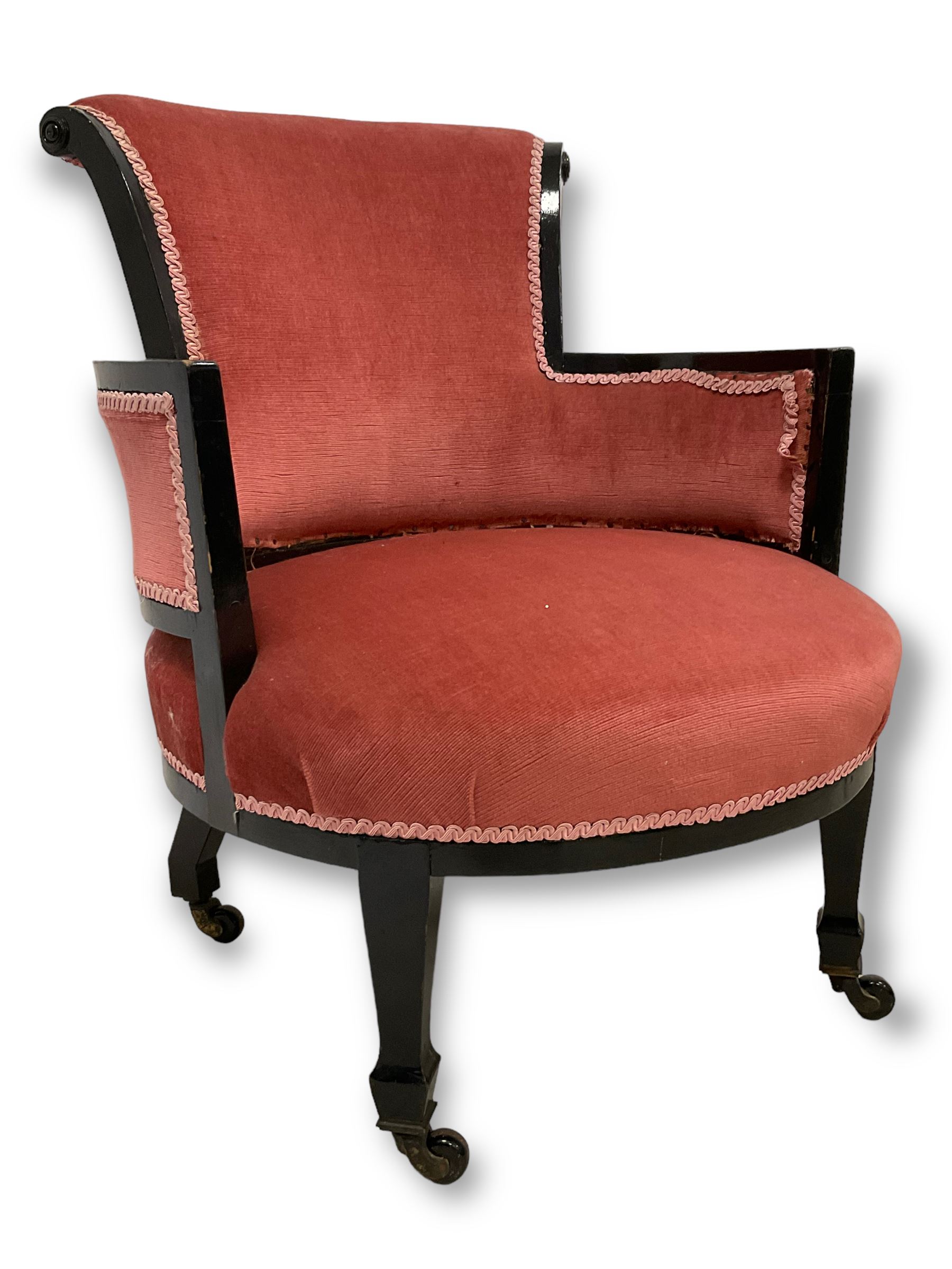 Early 20th century ebonised hardwood-framed armchair, rolled back and curved arms, upholstered in pink fabric, on square tapering front supports with spade feet, brass and ceramic castors 