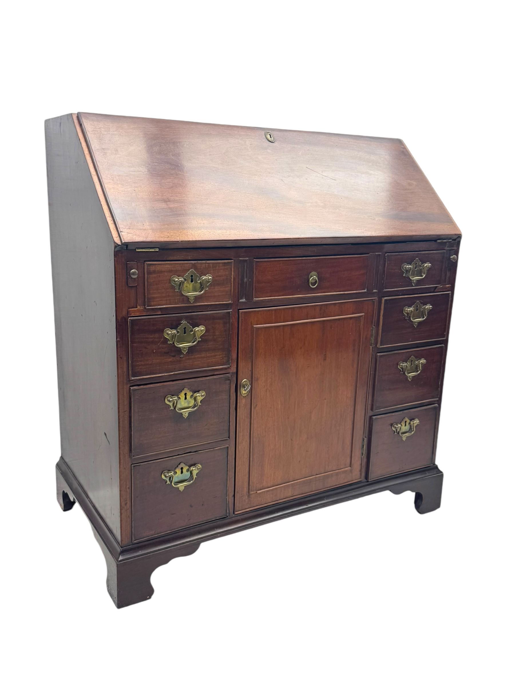 George III mahogany bureau, the fall-front enclosing fitted interior with pigeonholes and central cupboard, over an arrangement of nine short drawers surrounding a central cupboard, on shaped bracket feet