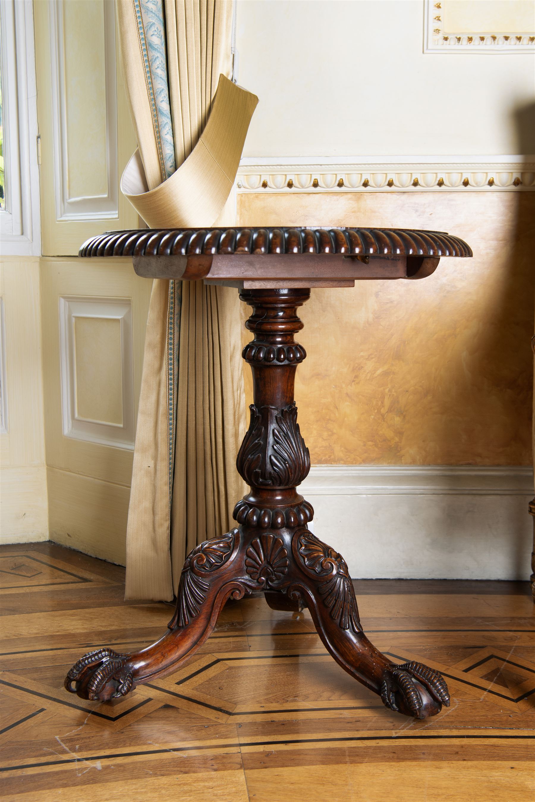 19th century rosewood tripod table, circular tilt-top with gadroon carved edge, turned column with lobed bands and curled acanthus leaf carved baluster, three out-splayed supports with shell carved knees and scaled ball and claw feet, 

Provenance:
Nidd Hall: acquired by Guy Reed from
Richard Butler, 17th Viscount
Mountgarret, in 1968