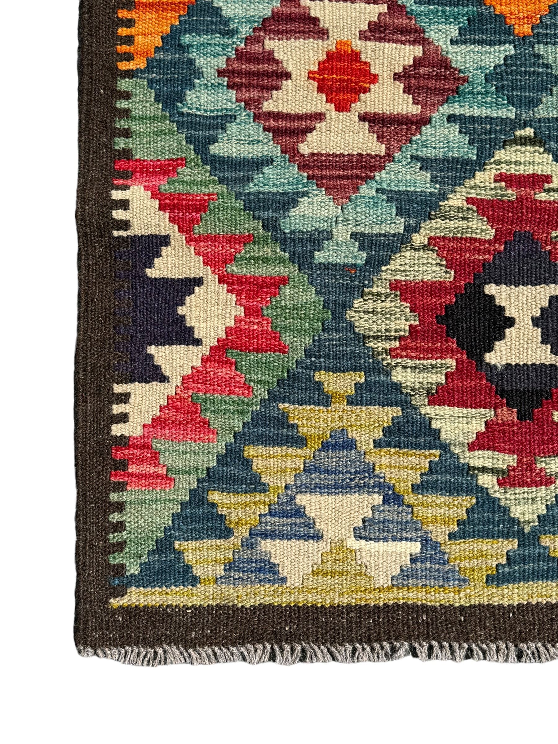 Maximana Kilim ground rug, the field decorated with a geometric pattern of multi-coloured diamonds and triangles, each containing stylised motifs, enclosed by a plain brown border