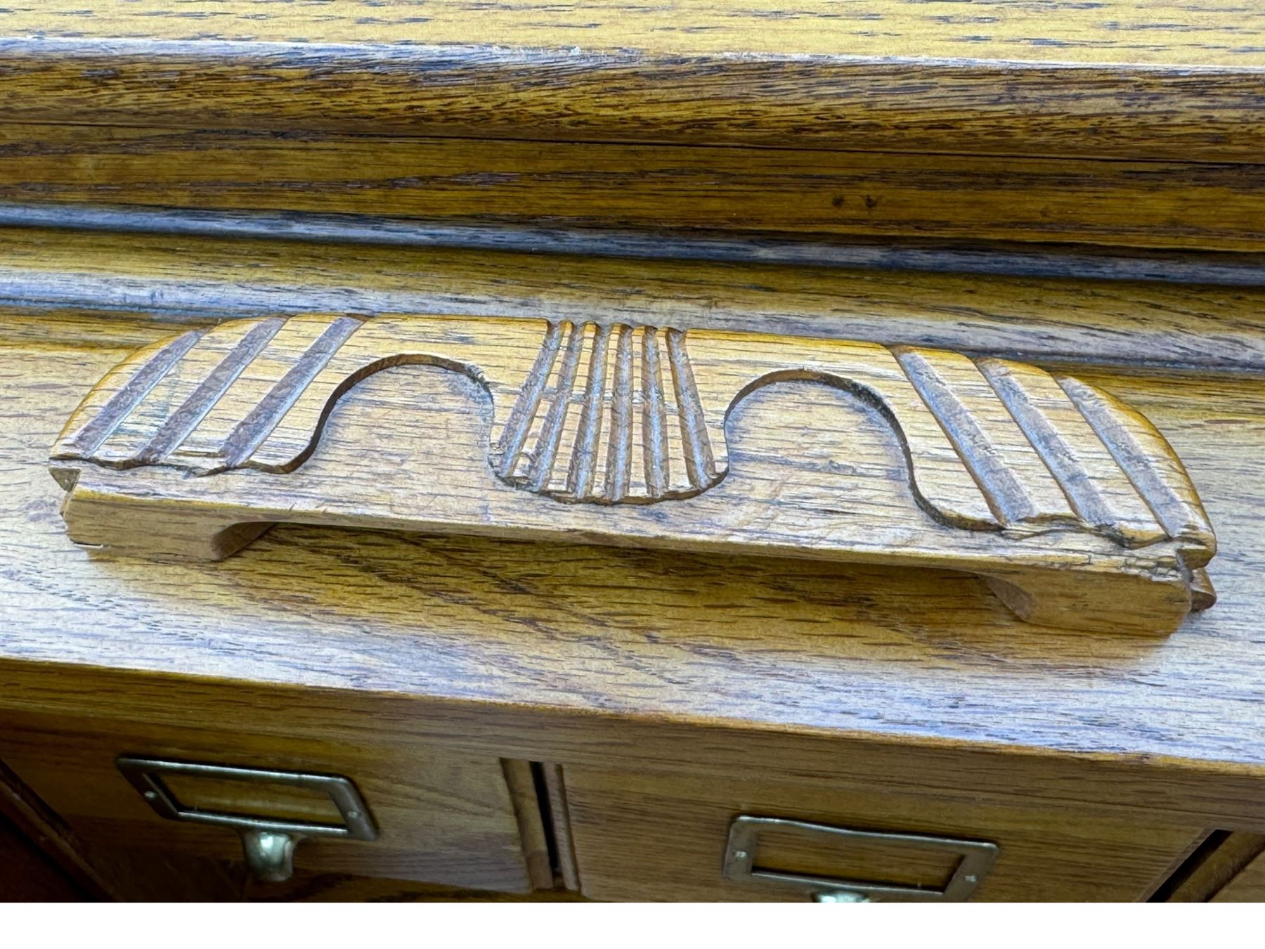 Early 20th century oak tambour roll-top desk, the top with fitted interior including drawers, pigeonholes and compartments, the twin pedestals fitted with four drawers with carved handles, supported by plinth base 