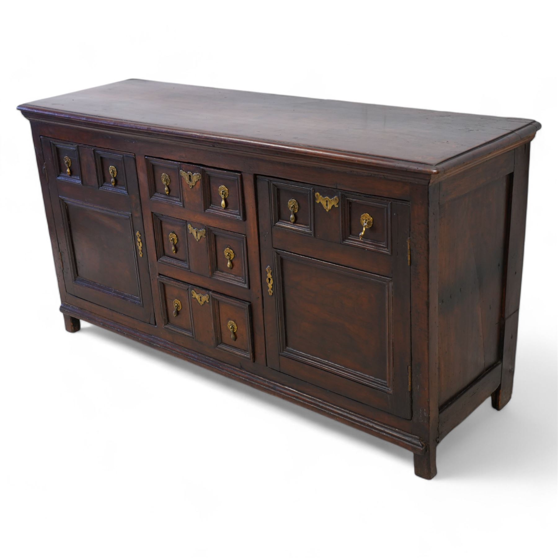 George III elm dresser base, the rectangular top with moulded edge, fitted with three central graduating twin-panelled drawers, flanked by two cupboard doors moulded with false drawer facias over large panels, lower moulded edge over stile feet