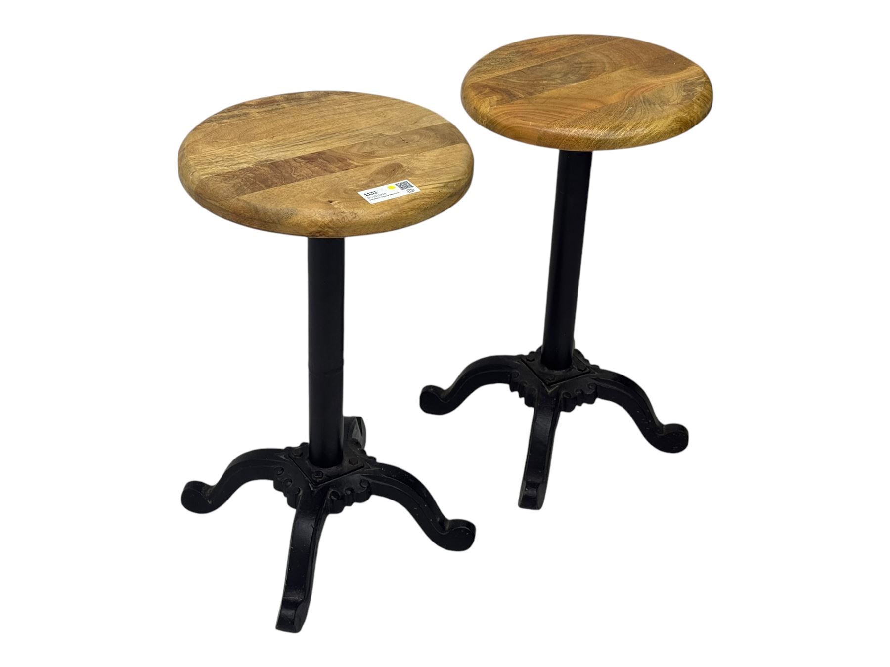 Pair of 20th century machinist stools, each with height-adjustable beechwood circular seats, supported by cast iron pedestal bases with four splayed feet