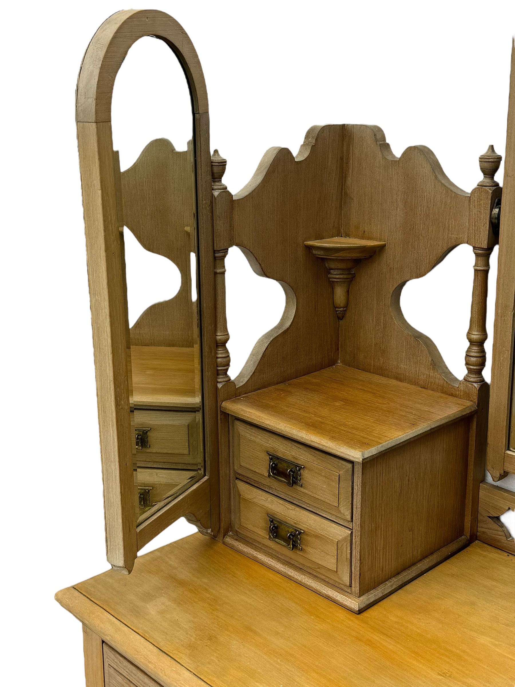 Late Victorian satin walnut dressing table, central mirror with carved crest flanked by two adjustable side mirrors, each supported by turned uprights, the base fitted with two short over two long drawers with brass handles, resting on bracket feet