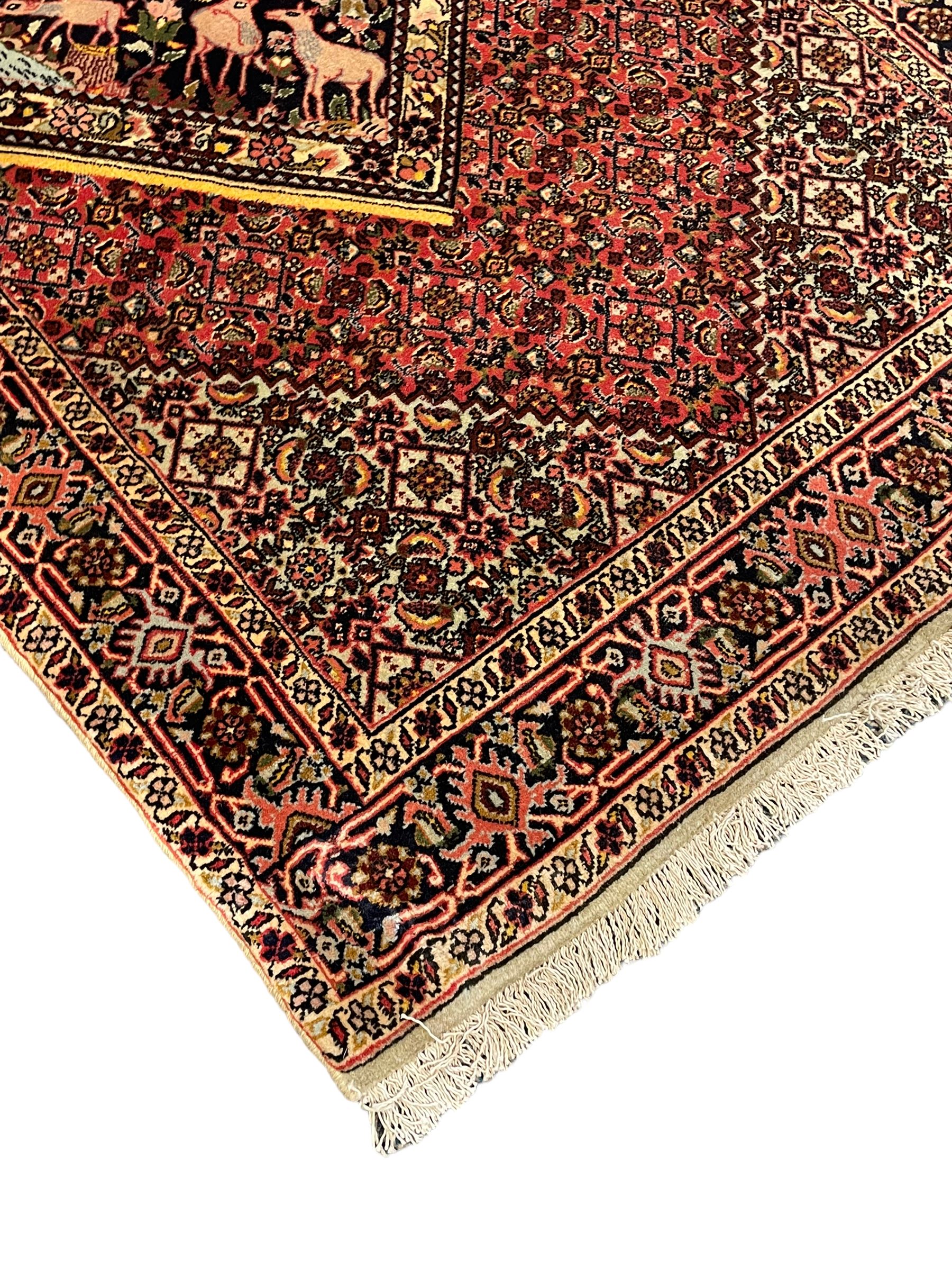 Persian Bidjar peach ground rug, the field decorated with repeating Herati motifs surrounding an off-centre lozenge medallion, decorated with grazing deer and peacock motids, the field border decorated with repeating stylised plant motifs, multiple floral design guard bands