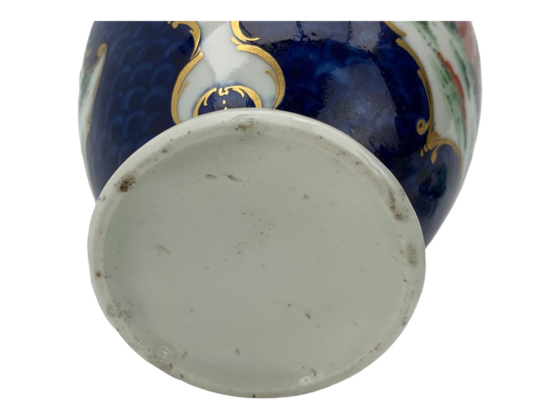 18th century Worcester tea caddy, of oval form and painted in the Kakiemon palette with reserves of flowers against a blue scale ground, H14cm together with a similar Worcester circular dish, painted with floral sprays, within a scalloped edge, blue crescent mark beneath, D19cm (2)