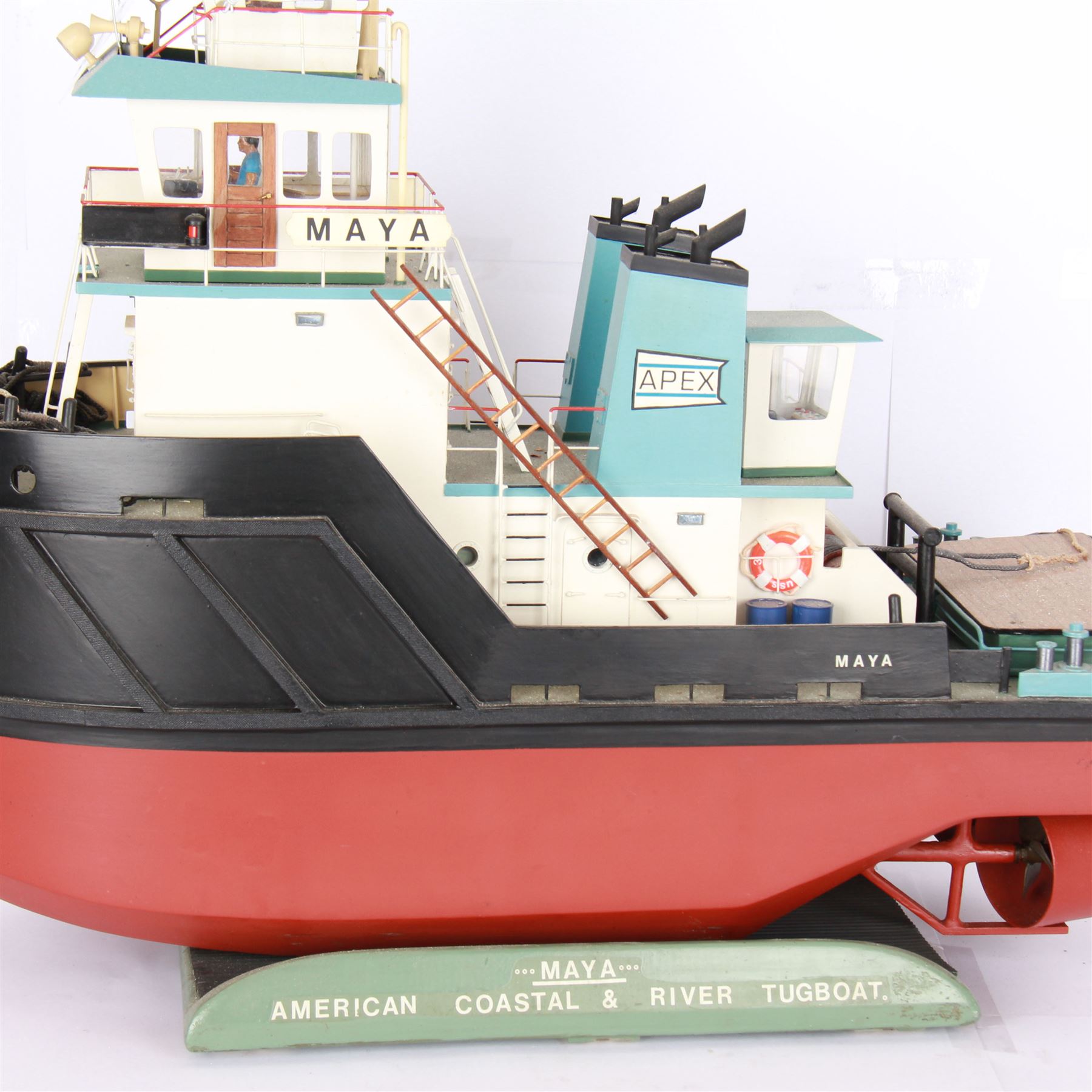 Modern model of American Coastal and River Tugboat 'Maya', in red, black and light blue finish, upon a green stand inscribed with name, H53cm, W52cm 