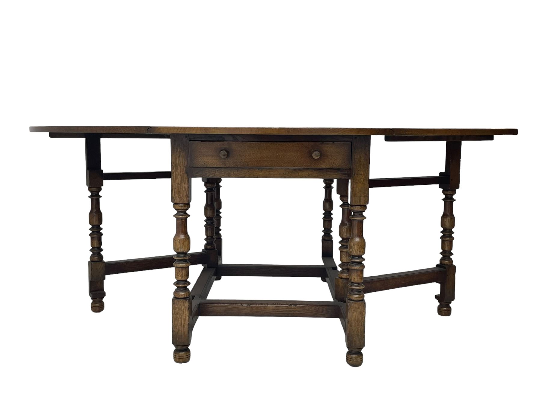 Titchmarsh & Goodwin - 17th century design oak drop leaf dining table, oval top with hinged drop leaves, single drawer to one side with applied makers label, baluster-turned supports united by stretchers