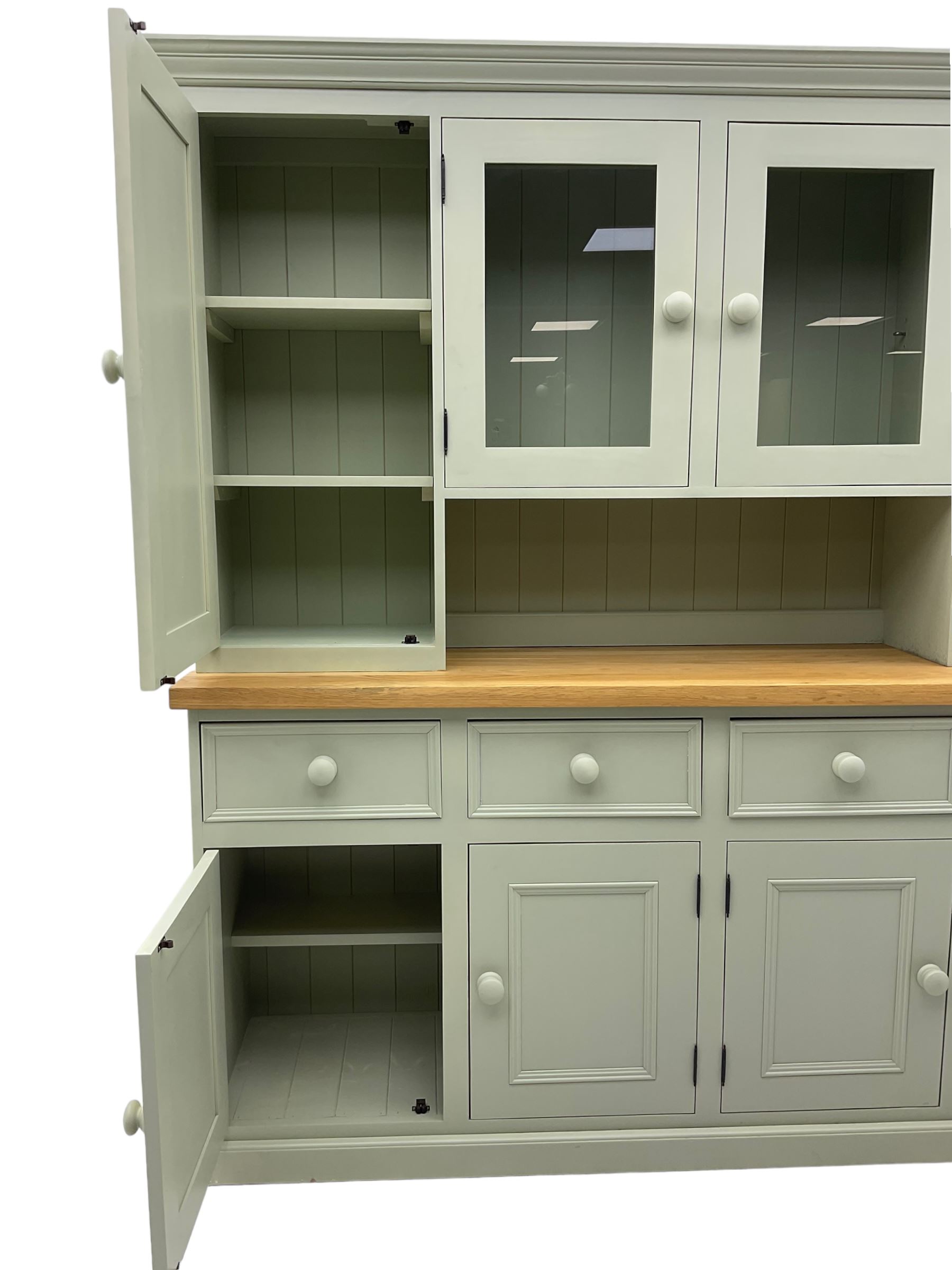 Painted kitchen dresser, projecting moulded cornice over central glazed display doors and flanking panelled cupboard doors, polished oak rectangular top over four drawers and four cupboards, on moulded plinth base, in laurel green paint finish 