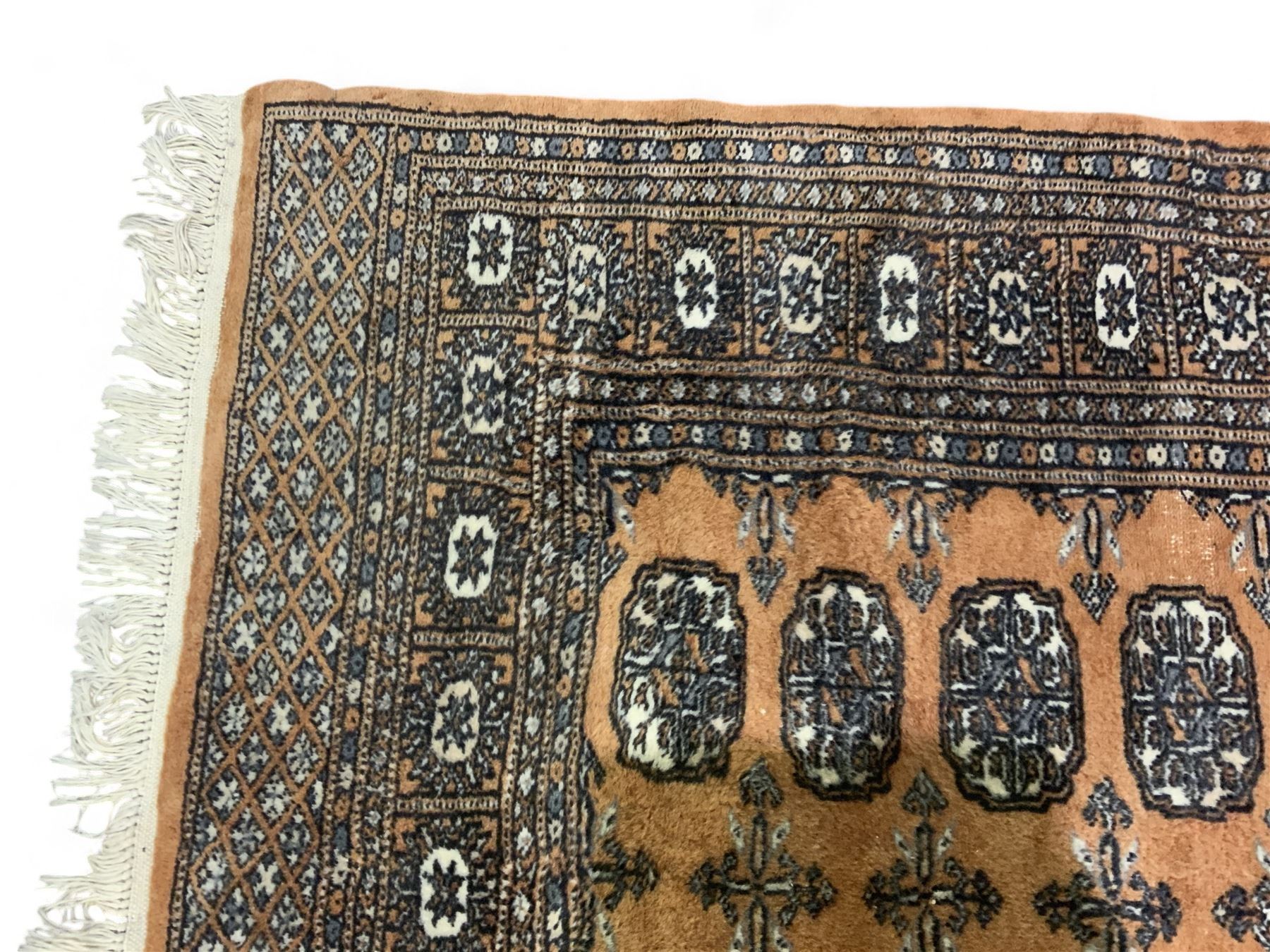 Afghan Bokhara rust ground rug, decorated with three columns of Gul motifs, the wide guard band with further scrolling and geometric designs (183cm x 129cm); together with a Persian design indigo ground rug (W170cm x 117cm)