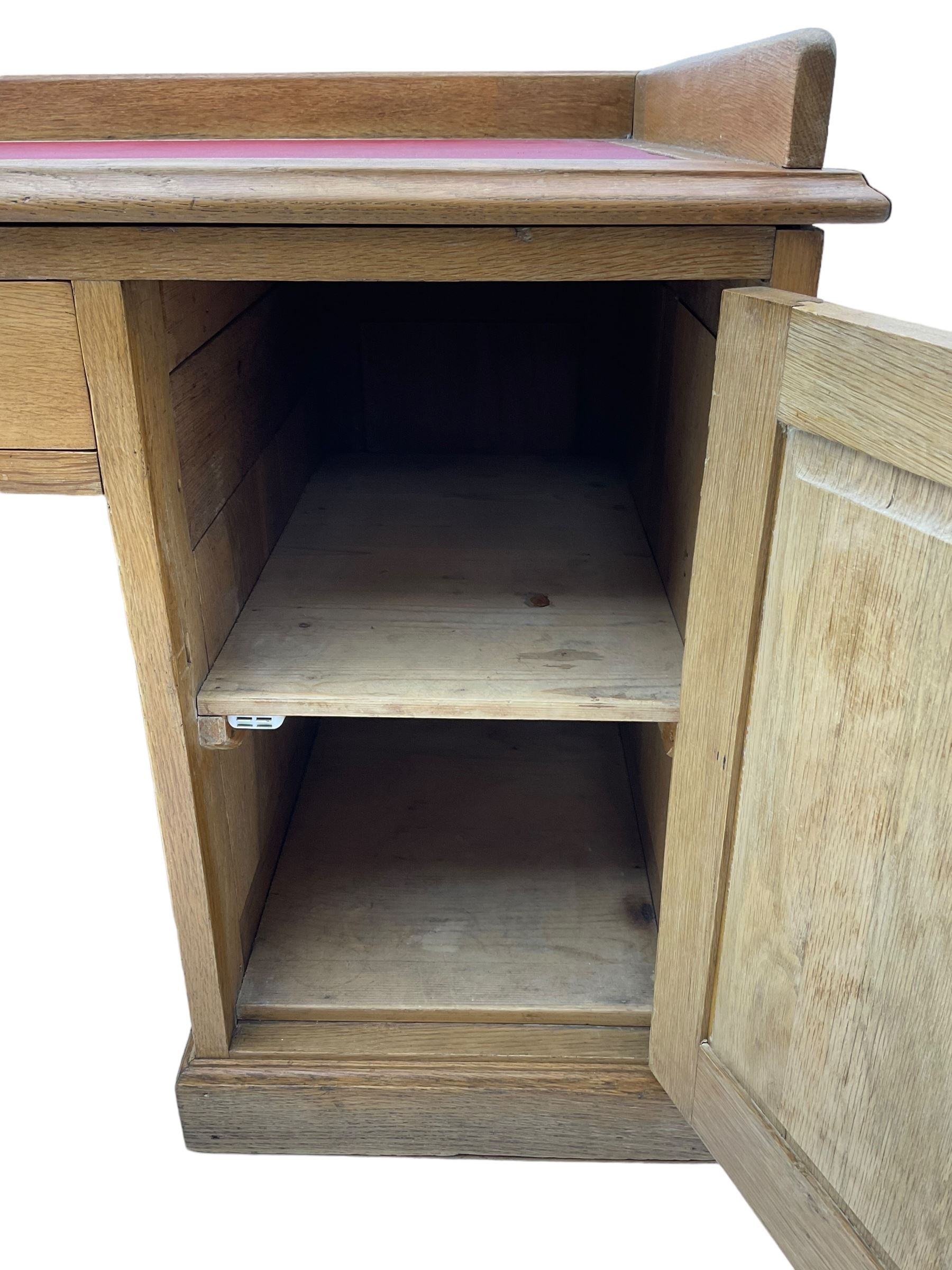 20th century oak desk, moulded rectangular top with raised back and inset leather writing surface, fitted with five drawers and single panelled cupboard, on moulded plinth base