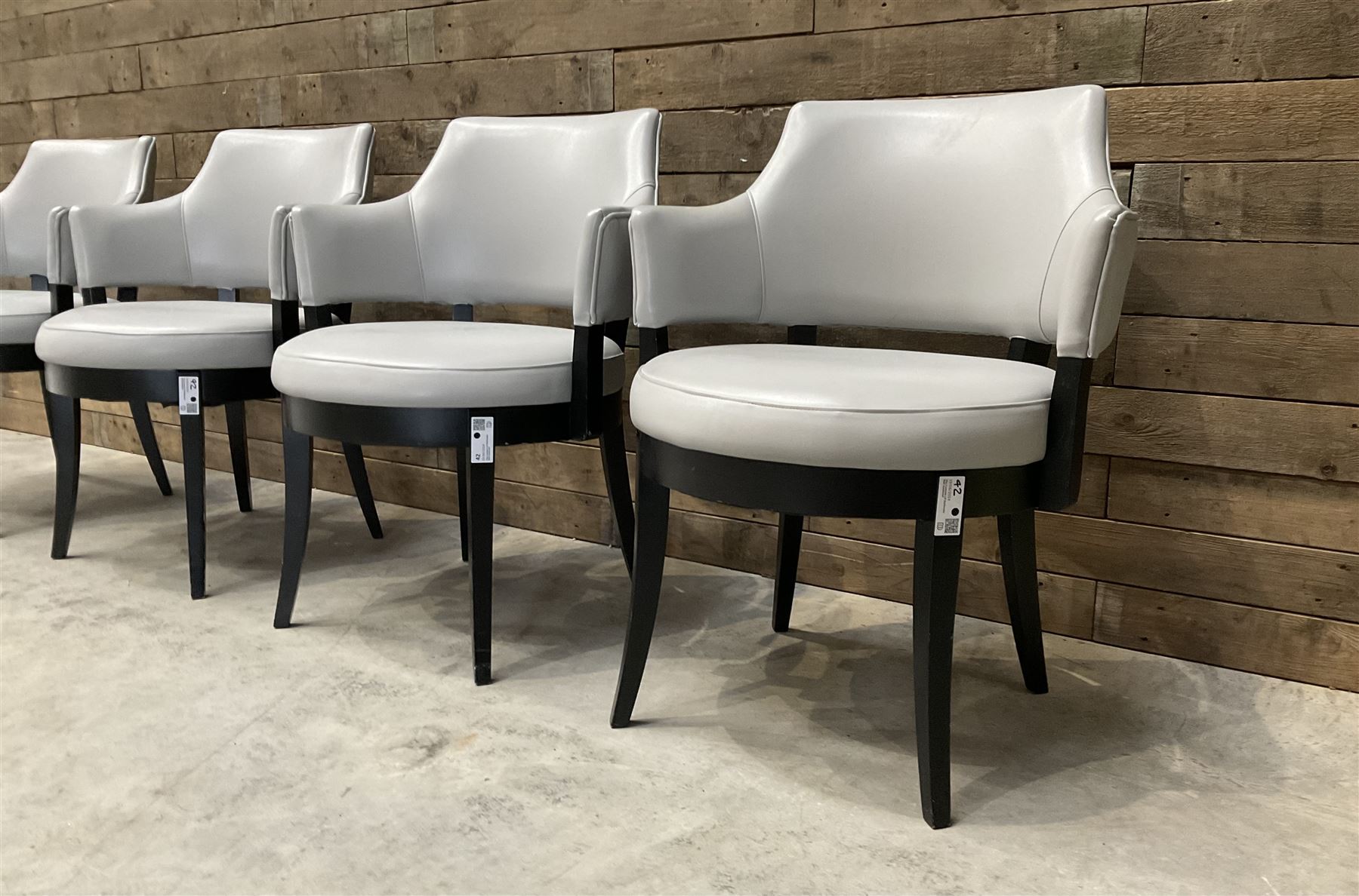 Four ebonised framed tub shaped armchairs, upholstered in grey fabric