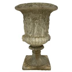 Cast stone Campana shaped urn, decorated with festival scenes over gadrooned underbelly, circular foot on square base