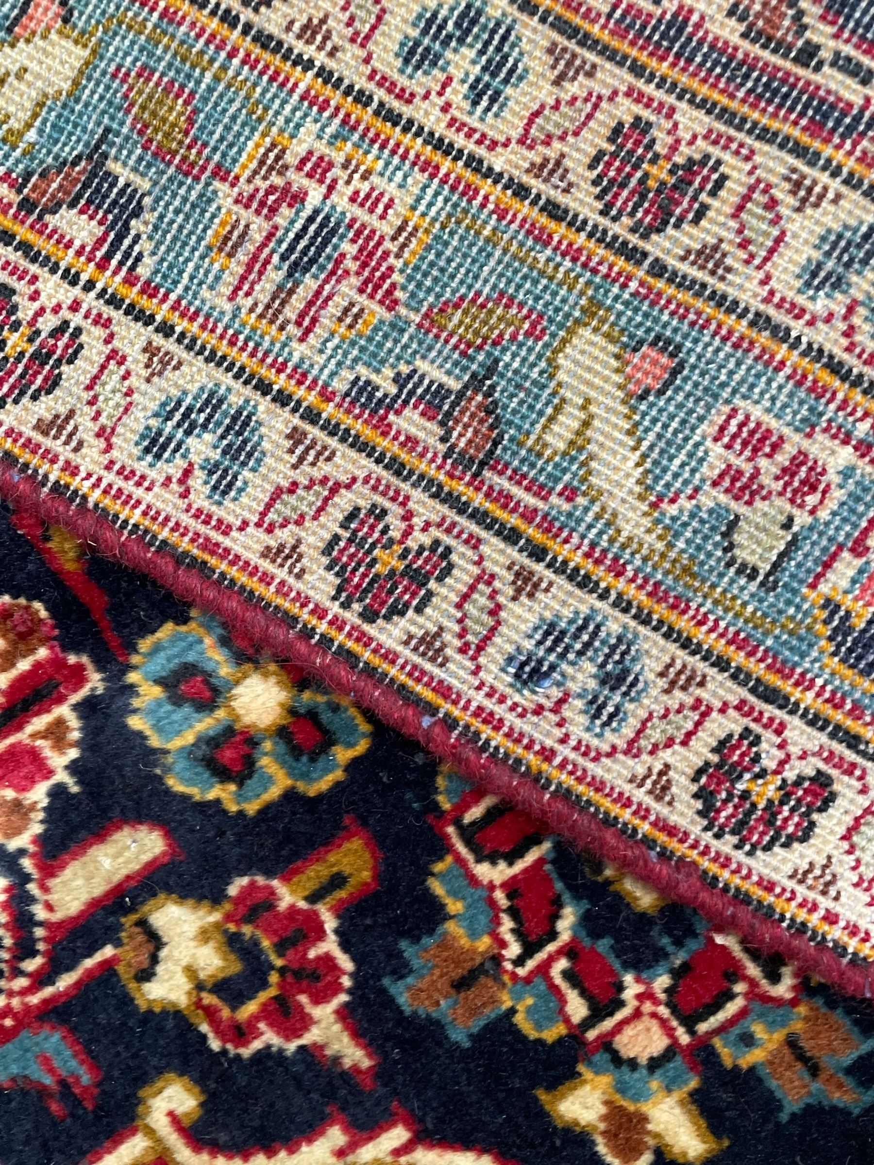 Persian Kashan crimson ground carpet, floral pattern pole medallion surrounded by trailing branches with foliate motifs and palmettes, scrolling border decorated with stylised plant motifs, within multiple guard stripes