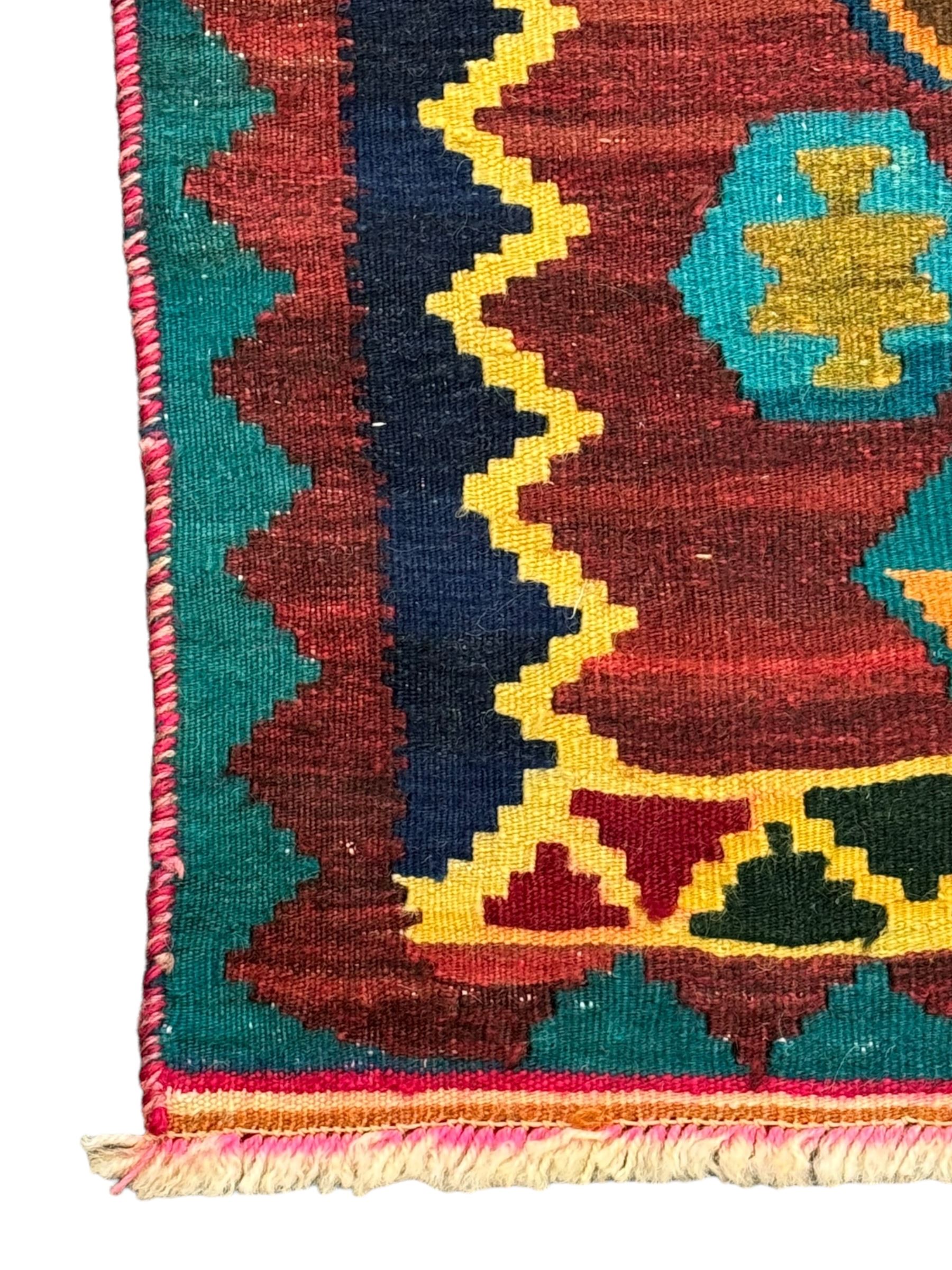 South West Persian Qashqai Kilim, crimson ground and decorated with three rows of geometric motifs, within zig-zag borders 