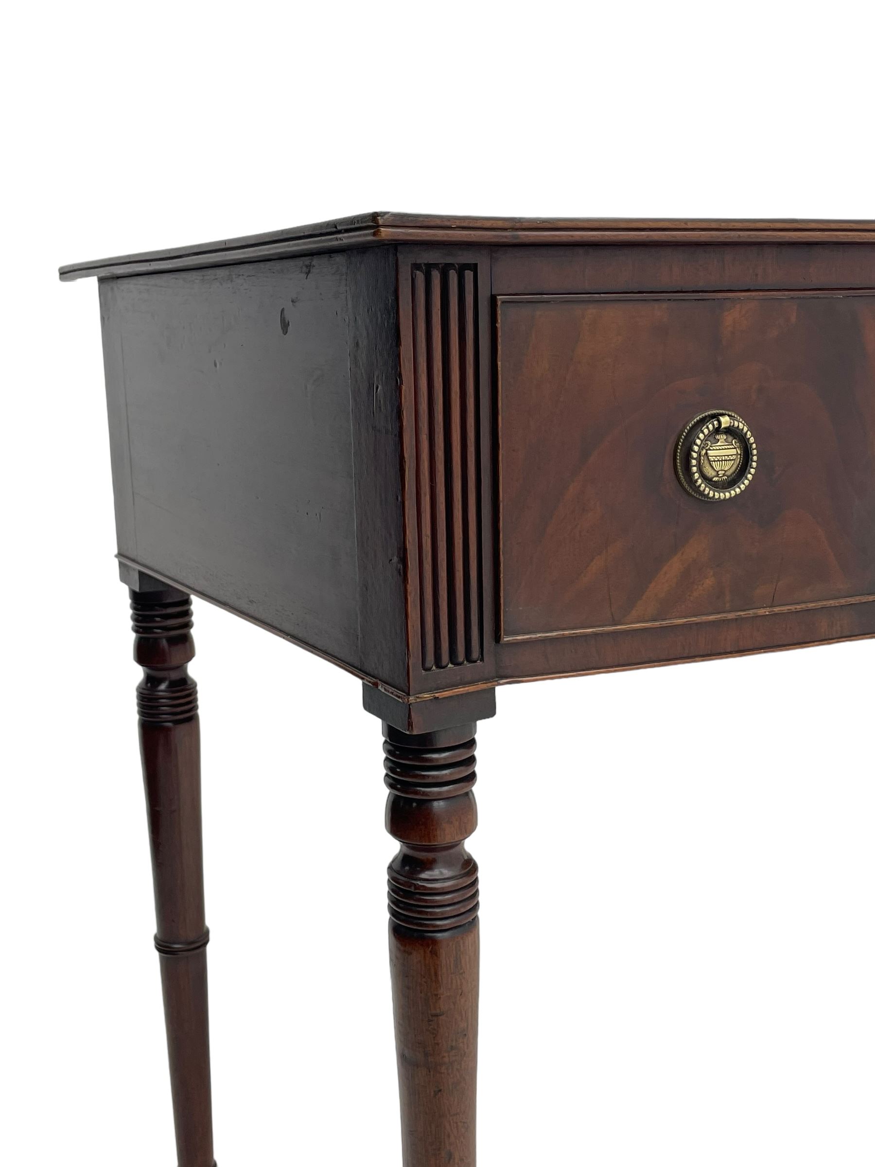 George III mahogany kneehole dressing or writing table, stepped bow-front form, reed moulded top with mahogany crossband, fitted with three cock-beaded drawers with circular pressed brass handle plates decorated with urn and beaded ring handle, on ring turned supports 