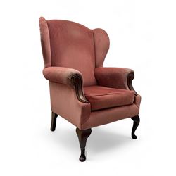 Queen Anne design wing back armchair, upholstered in coral fabric with carved mahogany arm...