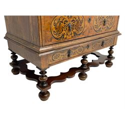 18th century inlaid walnut chest on stand, ovolo-moulded rectangular top inlaid with ebony panels each decorated with scrolling foliage, flower heads and birds, fitted with two short over three long drawers, the drawer fronts decorated with ebony panels enclosing curled leaf inlays, the base fitted with single drawer on turned supports united by waved stretchers, on turned bun feet 