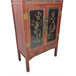 Late 19th century Chinese Qing dynasty red and black lacquered wood cabinet, Fujianese province, upper cupboard enclosed by two doors with relief carved and gilt panels depicting figures behind glass, the large cupboard enclosed by two panelled doors carved with trailing foliate branches and birds, inscribed with Chinese characters, to the left ‘Prolong life’ and to the right ‘Wealth and good fortune’, fitted with two drawers, square supports with carved brackets 