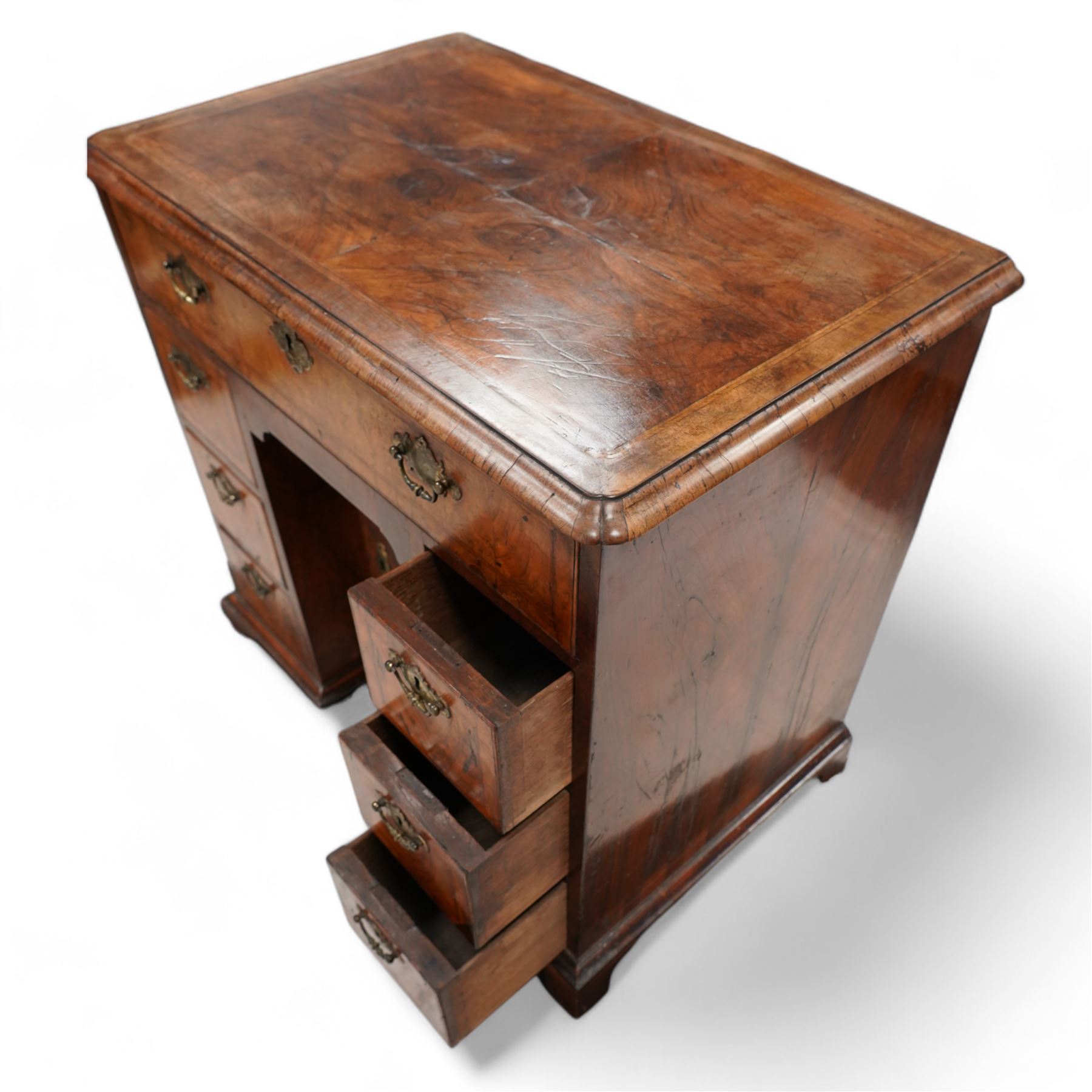 George II figured walnut knee-hole desk, the rectangular quarter-matched veneer top with moulded edge, crossbanding and feathered-banding, fitted with single frieze drawer over three drawers to each side, each with the central recess fitted with a single cupboard enclosing shelf, lower moulded edge on bracket feet