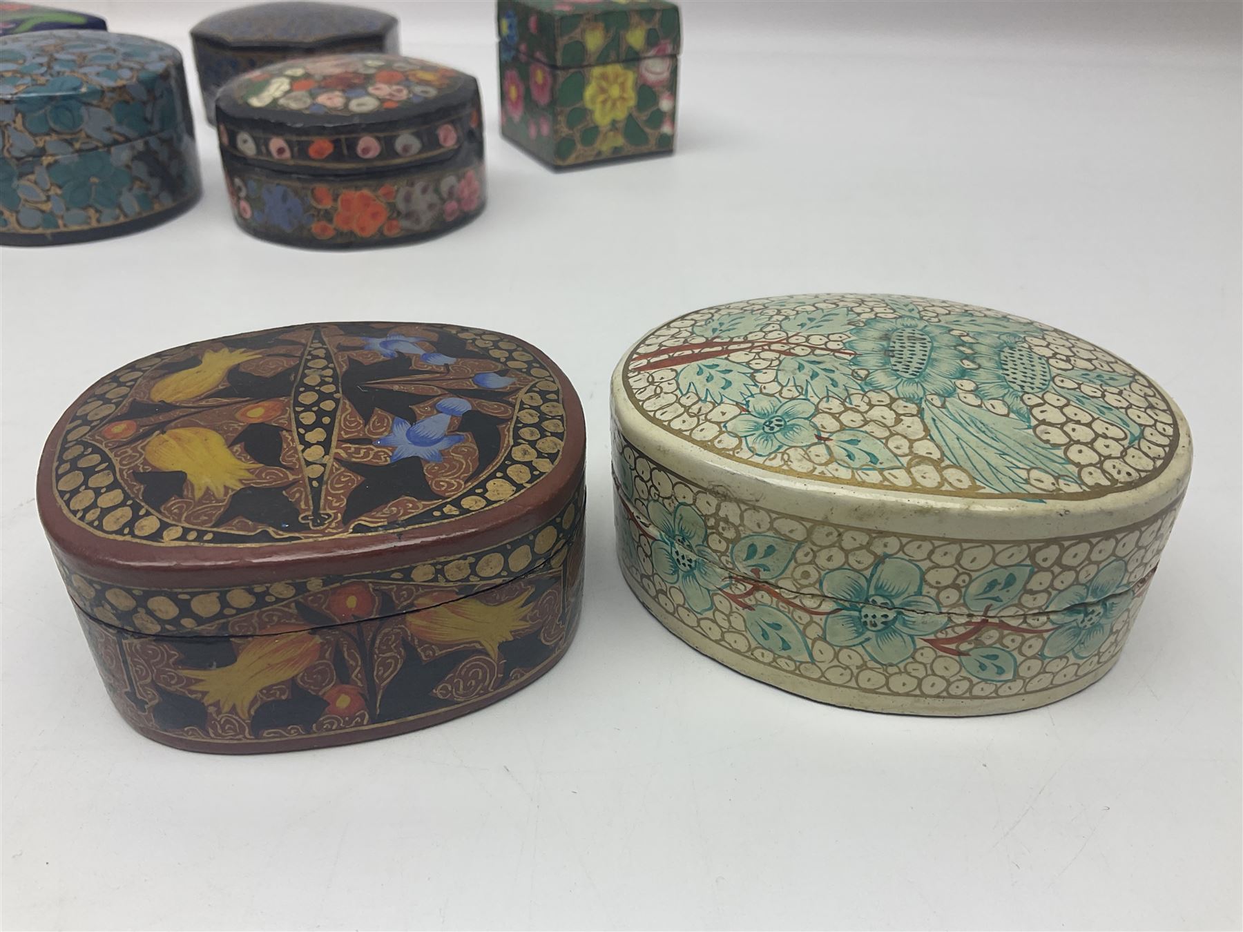 Twelve lacquered boxes, to include square and oval examples, with floral decorations, tallest H5cm