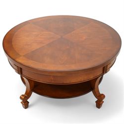 French cherry wood circular coffee table, segment veneered top with crossbanding over plain frieze, curved supports united by magazine under-tier, on spade feet