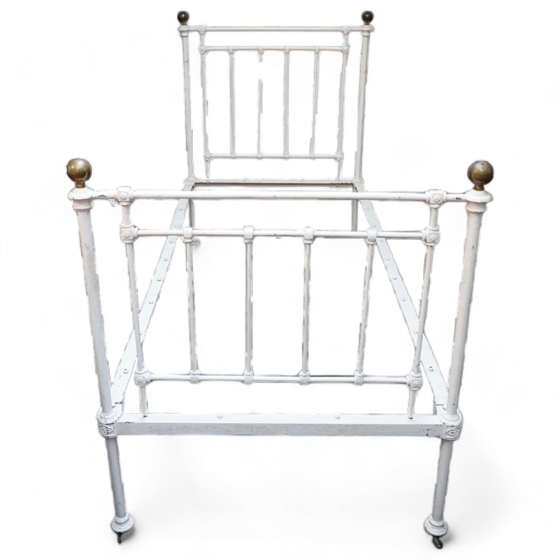 Victorian white painted cast iron 3' single bedstead, brass finials over floral moulded spindles, on castors