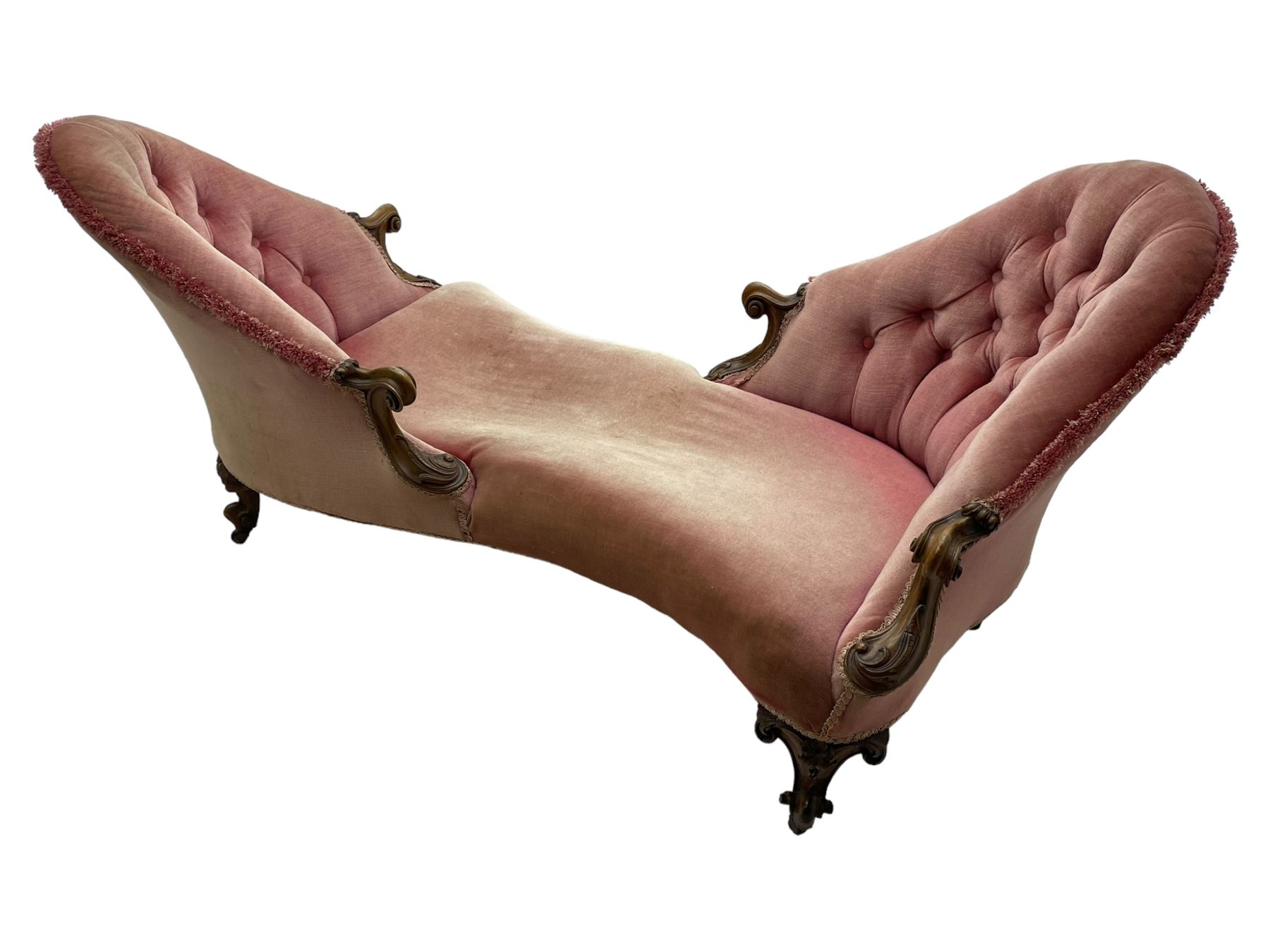 Victorian walnut framed tete-a-tete loveseat, scrolled arm terminals with moulded foliate decoration, buttoned backs and sprung seat upholstered in pale pink velvet, raised on cabriole supports with applied flower heads and scroll feet terminating to ceramic castors