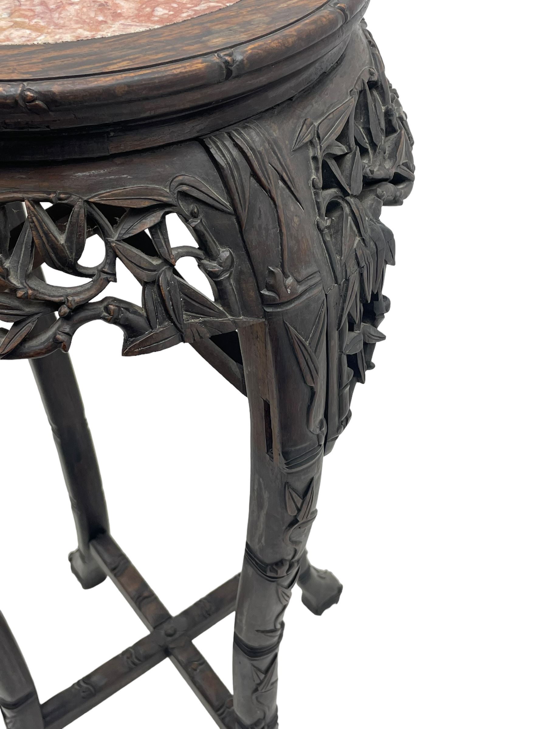 Early 20th century Chinese hardwood plant stand, circular top with marble inset, carved and pierced with interlacing foliage, on leaf carved supports united by x-framed stretchers