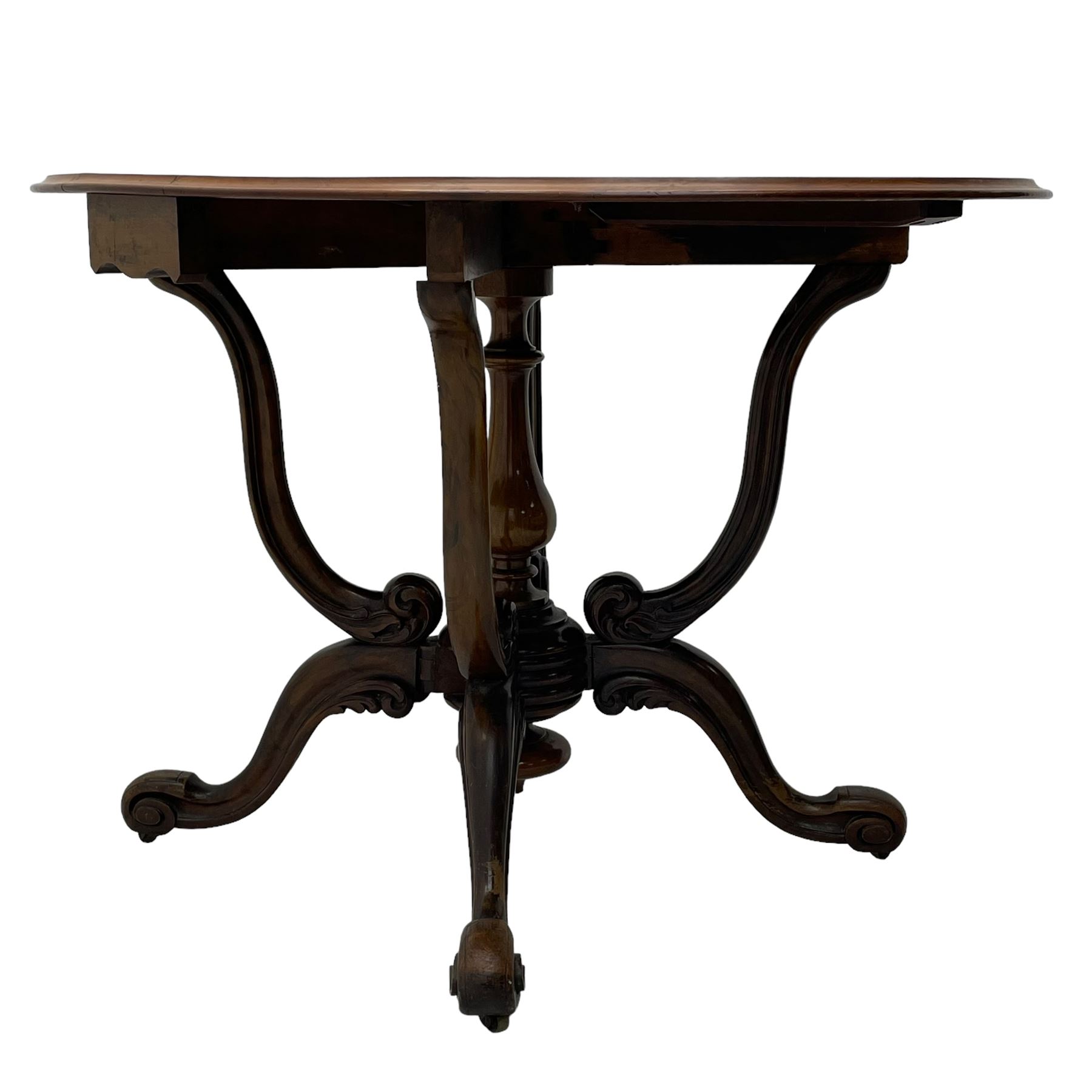 Unusual Victorian figured walnut drop-leaf Sutherland table, moulded drop-leaf oval top, central turned baluster column with quadruple moulded S-scroll supports carved with acanthus leaves, four out-splayed supports with scroll carved terminals, double gate-leg action base, on castors