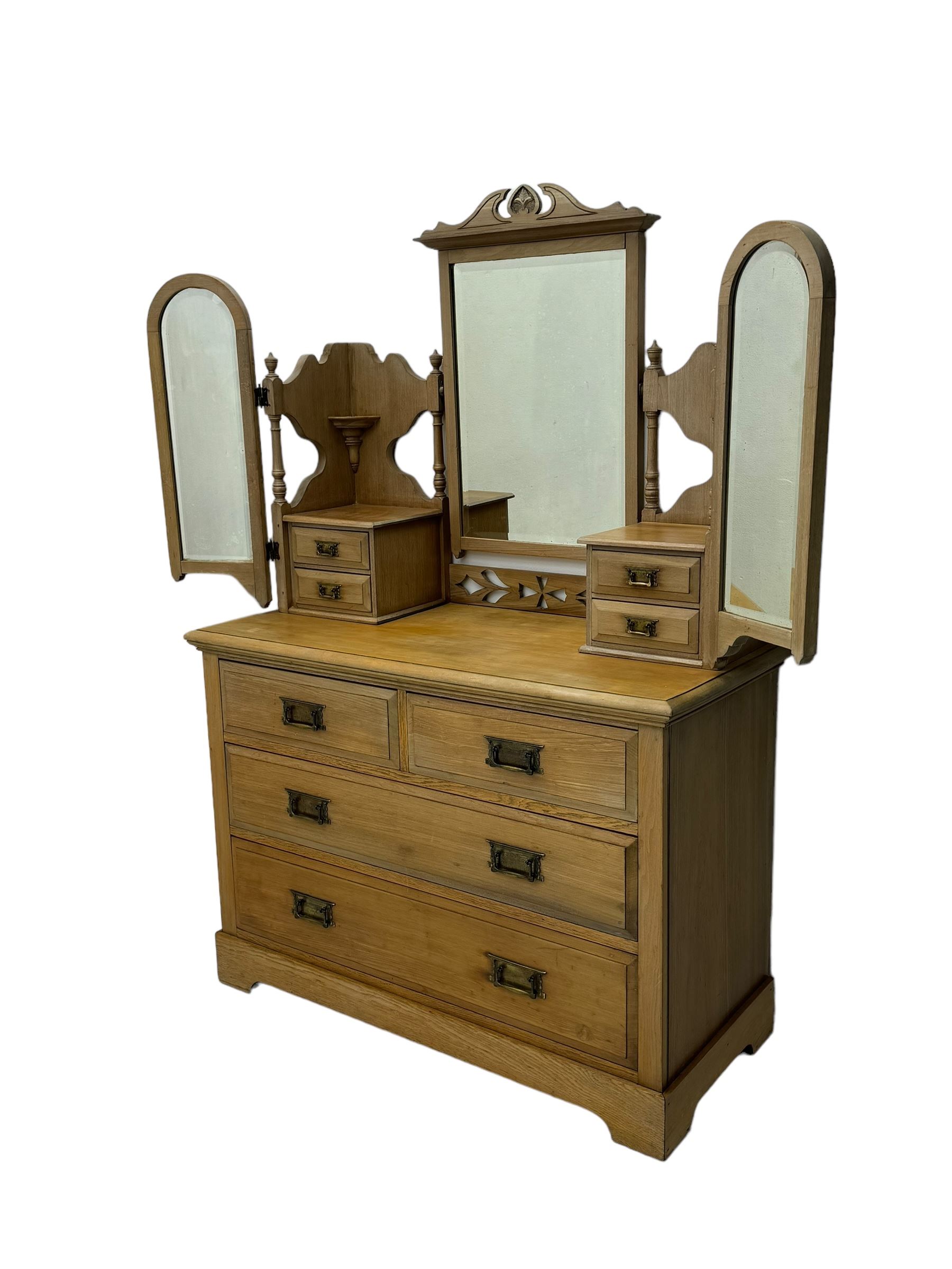 Late Victorian satin walnut dressing table, central mirror with carved crest flanked by two adjustable side mirrors, each supported by turned uprights, the base fitted with two short over two long drawers with brass handles, resting on bracket feet