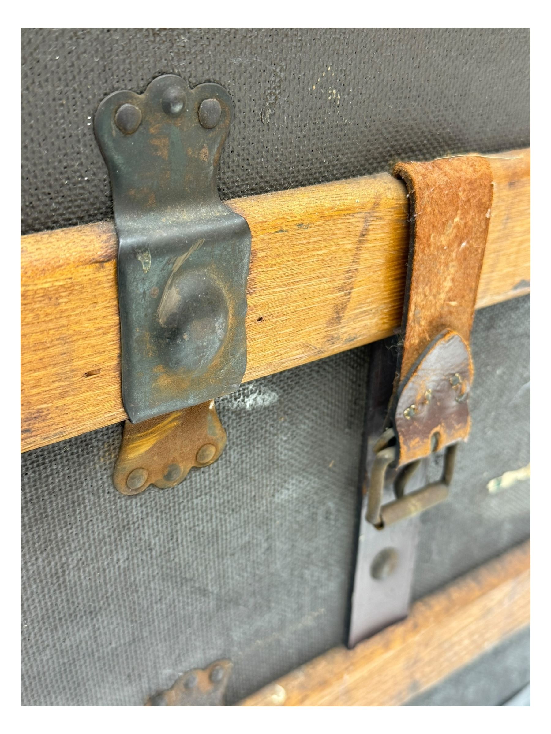 Early 20th century 'McBrine Baggage' steamer trunk, oak frame and black canvas covering, featuring metal hardware and leather straps, fitted with central lock, additional latches, and corner protectors, the interior is lined with floral-patterned paper and includes a removable top tray with makers label 