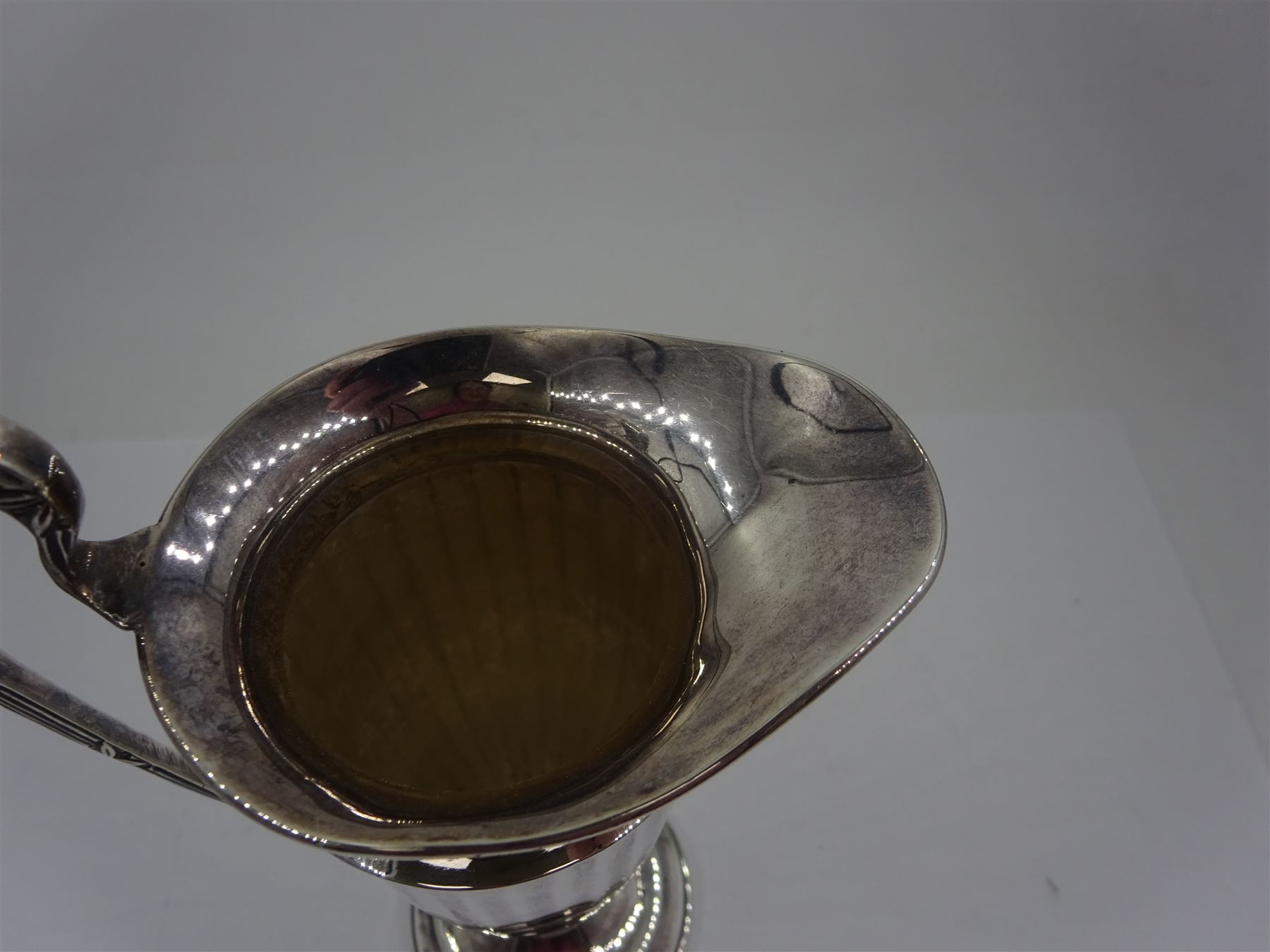 Early 20th century silver cream jug, of helmet form with faceted body and scroll handle, upon stepped circular foot, hallmarked Walker & Hall, date mark indistinct, H16.5cm