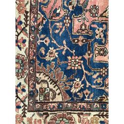 Persian Hamadan ground rug, central medallion design with a salmon pink field, accentuated by navy blue spandrels, surrounded by a stylised floral border in cream and blue tones