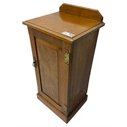 Edwardian oak bedside cabinet, raised back over moulded top, enclosed by panelled door, the interior fitted with shelves, on chamfered plinth base 