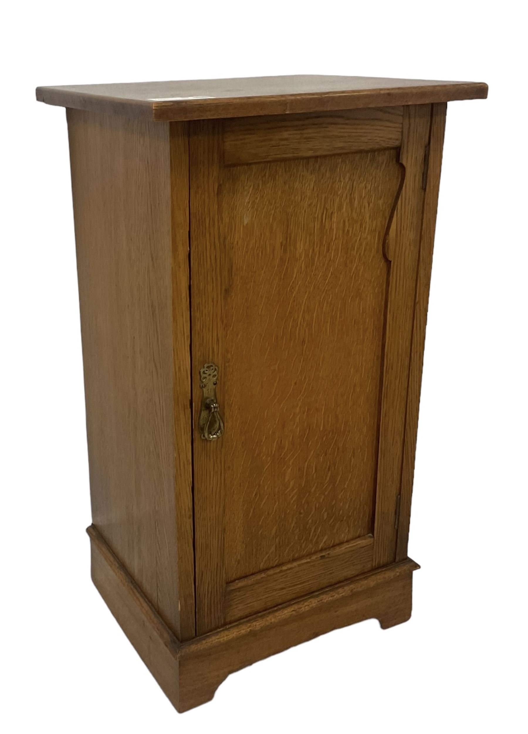 Arts and Crafts period oak pot cupboard, shaped panelled door enclosing single shelf