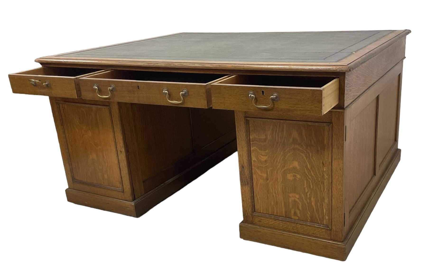 Late 19th century twin pedestal oak partner's desk, rectangular top with inset green leather writing surface, fitted with nine graduating drawers to each side, the rear drawers enclosed by panelled cupboards