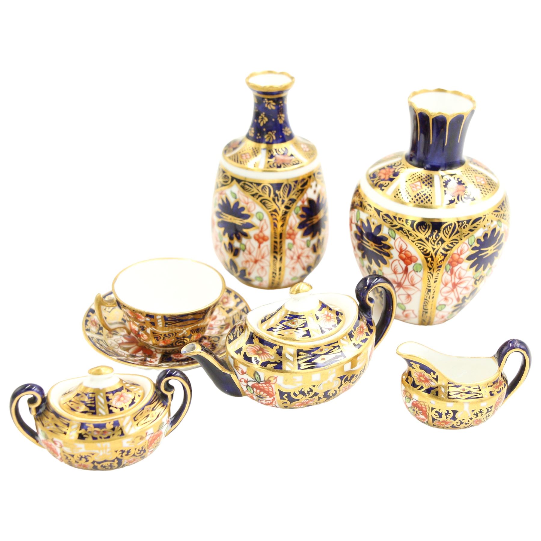 Royal Crown Derby miniature tea set of oval design decorated in Imari design 6299 comprising teapot, two handled sucrier and cover, milk jug and cup and saucer, date code 1905/6 and two small vases pattern 1129, date code 1907 H8.5cm