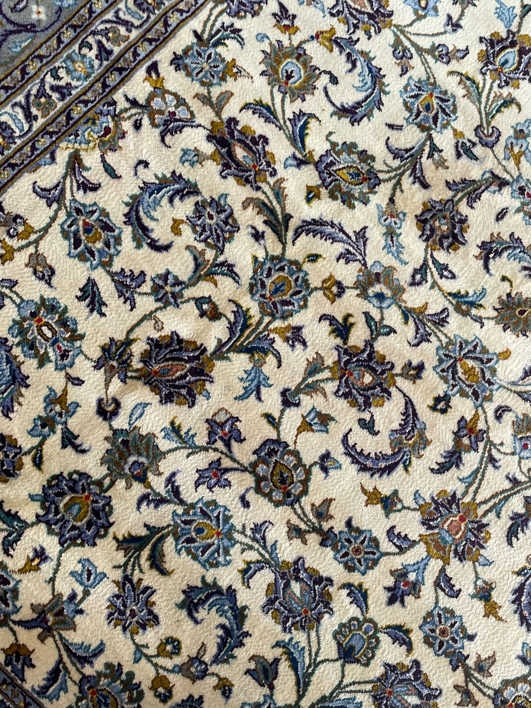 Persian Kashan ivory ground carpet, the busy field decorated with scrolling and interlaced leafy branches and palmettes, trailing branch border with repeating stylised plant motifs, within floral pattern guard stripes 