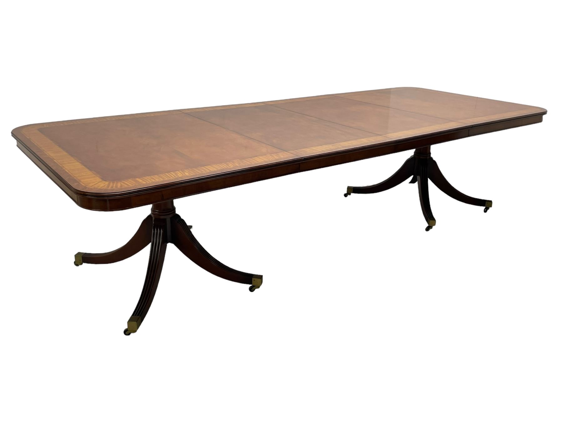 RBC Furniture (Made in England) - Georgian design mahogany dining table, rectangular top with rounded corners, satinwood and burr walnut bandings, two D-ends with two additional leaves and support rails, on barrel turned pedestals with four out-splayed reeded supports, brass cups and castors 