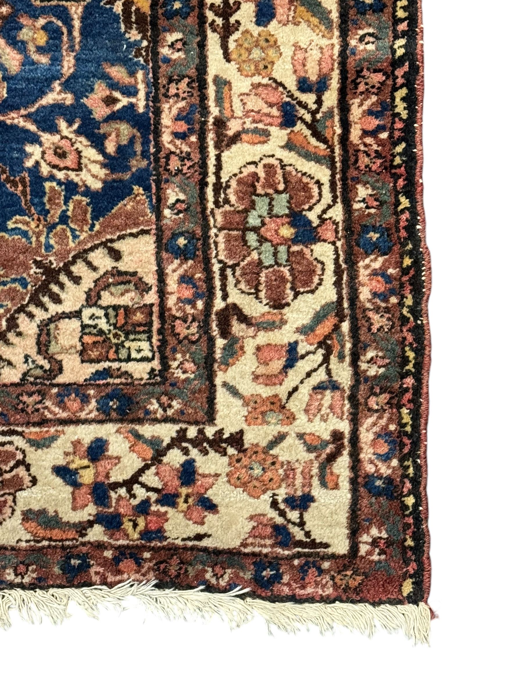 Persian Hamadan ground rug, central medallion design with a salmon pink field, accentuated by navy blue spandrels, surrounded by a stylised floral border in cream and blue tones